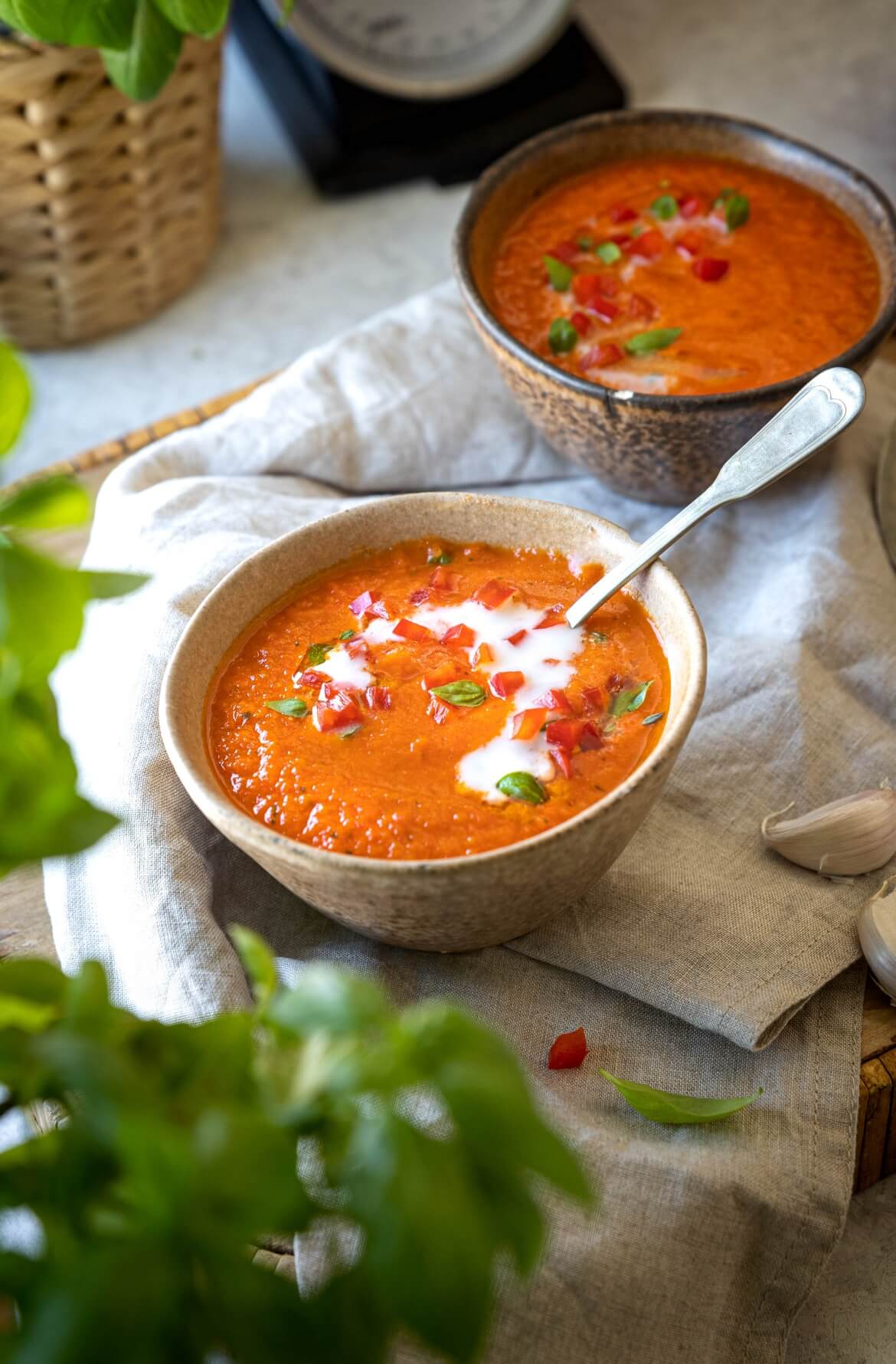 Duas taças com sopa de pimentos assados e uma colher dentro da sopa