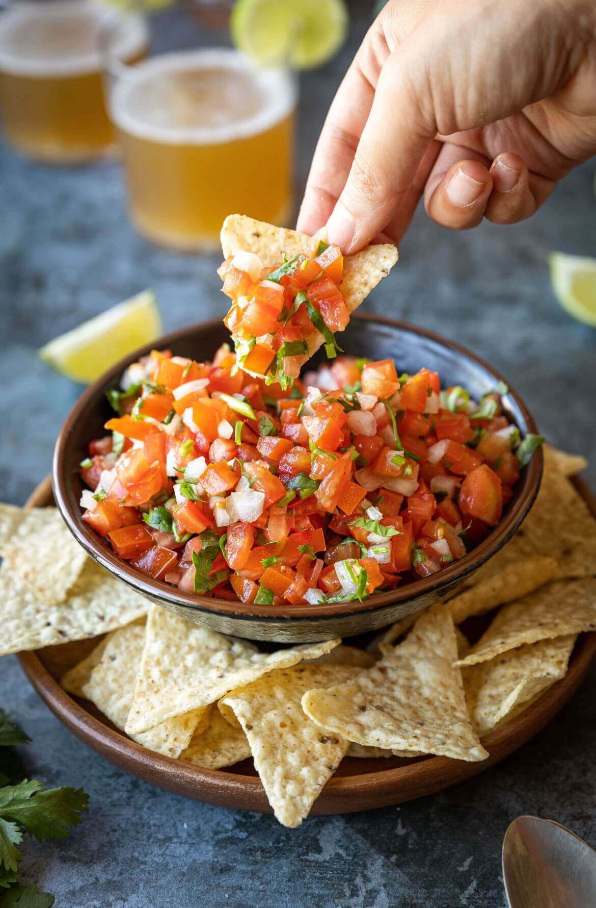 Uma taça com pico de gallo e uma mão a segurar uma tortilha