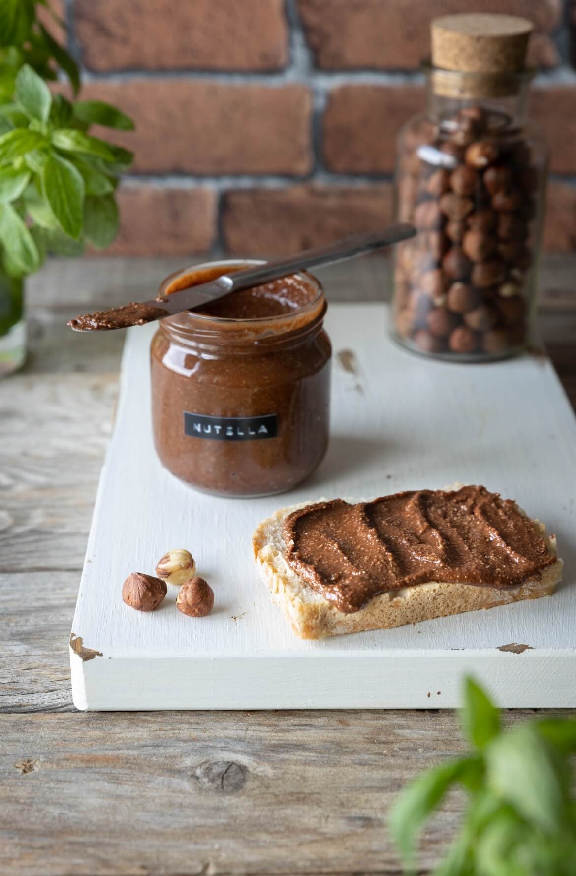 um frasco com uma faca e um pão barrado com nutella saudável caseira