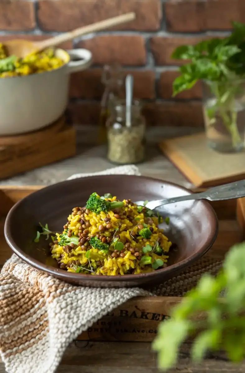 um prato fundo com arroz de lentilhas amarelo com brócolos