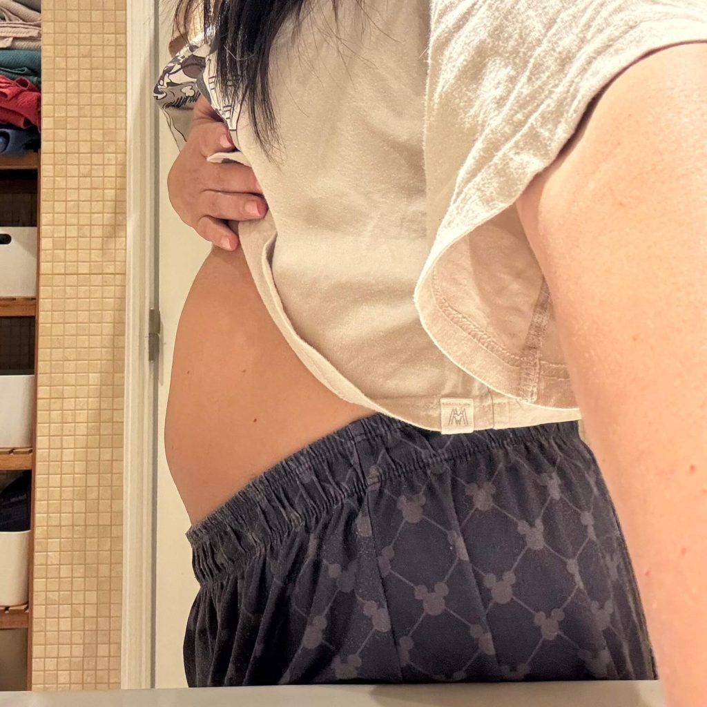 Barriga inchada vista de perfil, com a t-shirt clara levantada