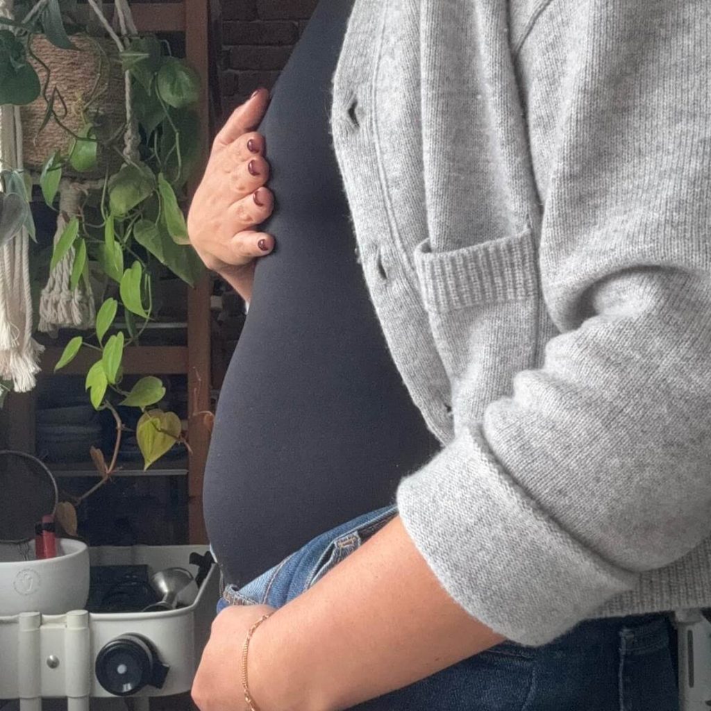 Barriga inchada vista de perfil, com casaco cinzento